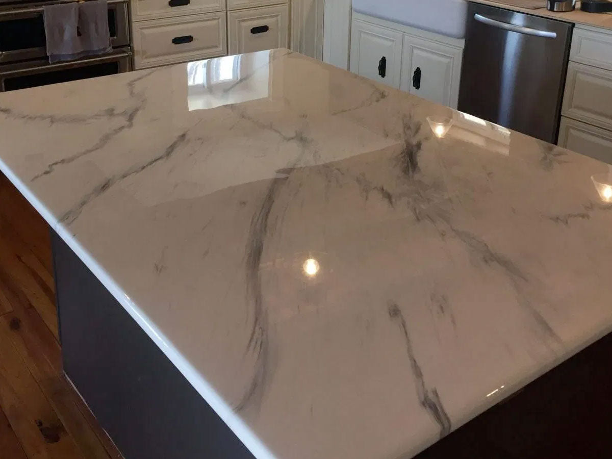 A kitchen island coated with clear table top epoxy, cured to a glossy, glass-like white marble finish with the coating carried over the edge.