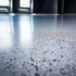 Garage floor with 50% black and white epoxy flake broadcast on a light gray base. This shows a Matte 2 part Water Based Urethane finish by Mckinnon Materials